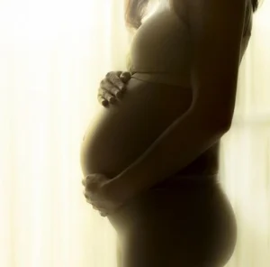 L'art d'attendre sans stress : Transformer l'impatience en alliée 2 Attendre sans stress femme enceinte avec ses mains posées sur le ventre symbolisant le positif de l'attente