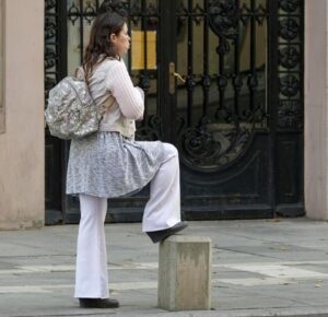 attendre femme qui attend debout les bras croisés un pied sur un poteau