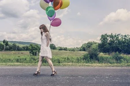 blues de l'anniversaire. femme seule marchant dans la rue avec des ballons