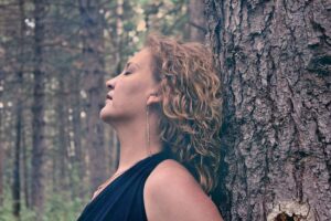 6 astuces pour s'adapter au changement d'heure 6 Changement heure. Femme appuyée contre un tronc d'arbre